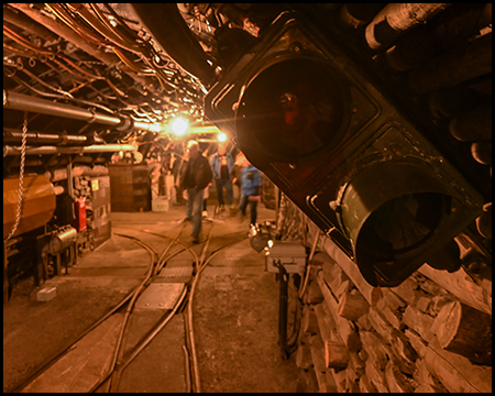 Ampel vor einer Weichenkreuzung für Grubenbahnen in einem Stollen. Zu sehen sind auch einige Besuchende.