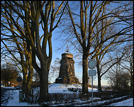 Steinerner Bismarkcturm in einer schneebedeckten Landschaft mit winterlichen Bäumen