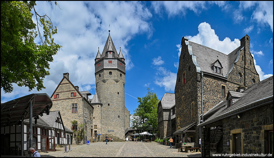 Burghof der Burg Altena mit mehreren historischen Gebäuden aus Naturstein und einem zentralen Turm