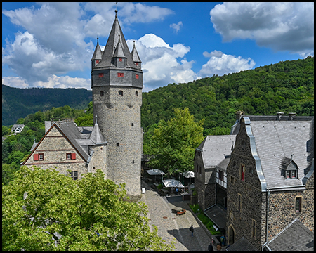 Ein Burghof mit alten Gebäuden und einem Turm aus erhöhter Position gesehen