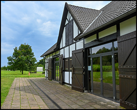 Fachwerkgebäude und weitläufiger Garten mit Wiesen und Bäumen