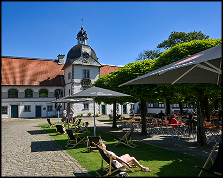 Liegestühle unter Bäumen vor einem alten Gebäude