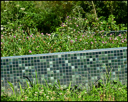 Eine mit grünlich-bläulichen Mosaiksteinen besetzte Mauer