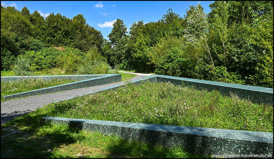 Mit Mosaikfliesen besetzte niedrige Mauern mit Wildblumenbeeten