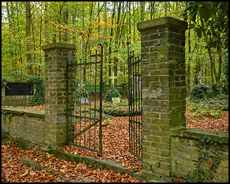 Tor in einer Mauer zu einem Friedhof im Wald