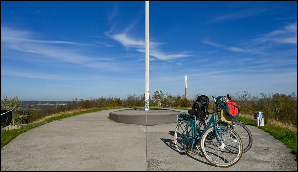 Ellipsenförmiges Plateau mit zwei Fahrrädern und einer weißen, hohen Lichtsäule