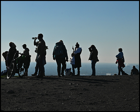 Menschen auf einem Berggipfel als schwarze Silhouette gegen den hellen Hintergrund