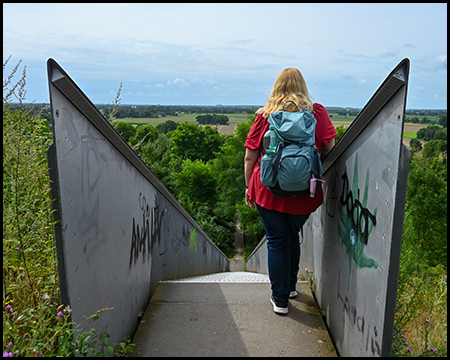 Eine Frau lehnt an einem Treppengeländer an an einem Berg