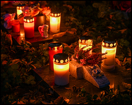 Leuchtende Grablichter auf einem Grab im Dunkeln