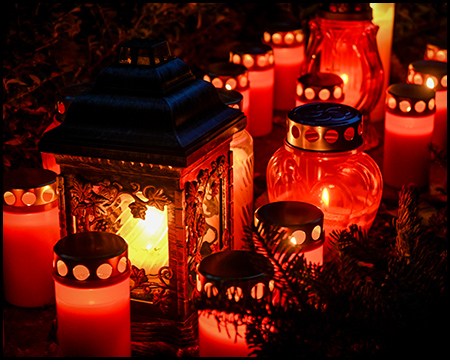 Viele leuchtende Grablichter auf einem Grab in der dunkelheit