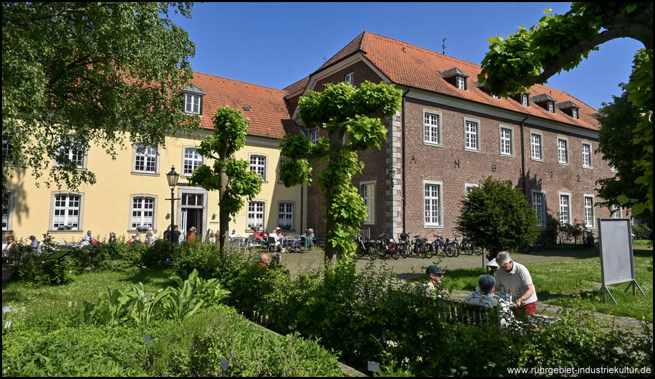Zwei historische Gebäude und ein Garten im Vordergrund bei schönem Wetter