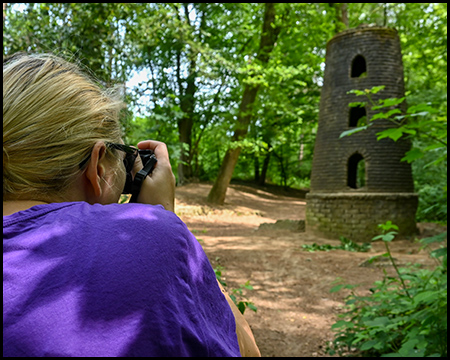 Eine Frau fotografiert einen Stumpf einer Windmühle im Wald