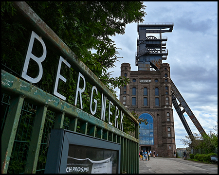 Ein Tor mit eisernen Buchstaben "Bergwerk", dahinter ein Förderturm