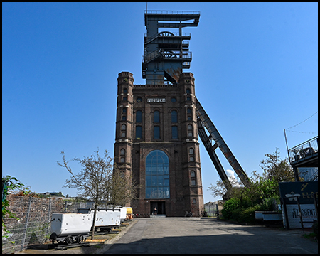 Ein Förderturm mit aufgesetztem Fördergerüst bei blauem Himmel