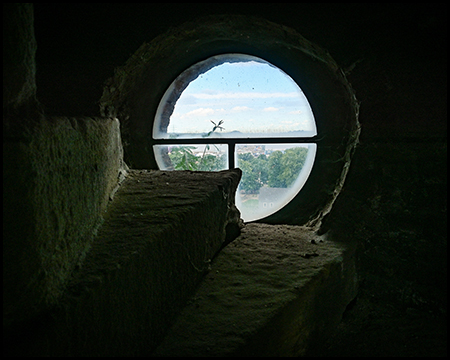 Ein rundes Fenster und im Dunkeln liegende Steintreppen