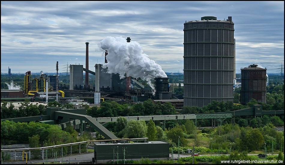 Blick auf eine Kokerei mit Gasometer und dampfendem Löschturm