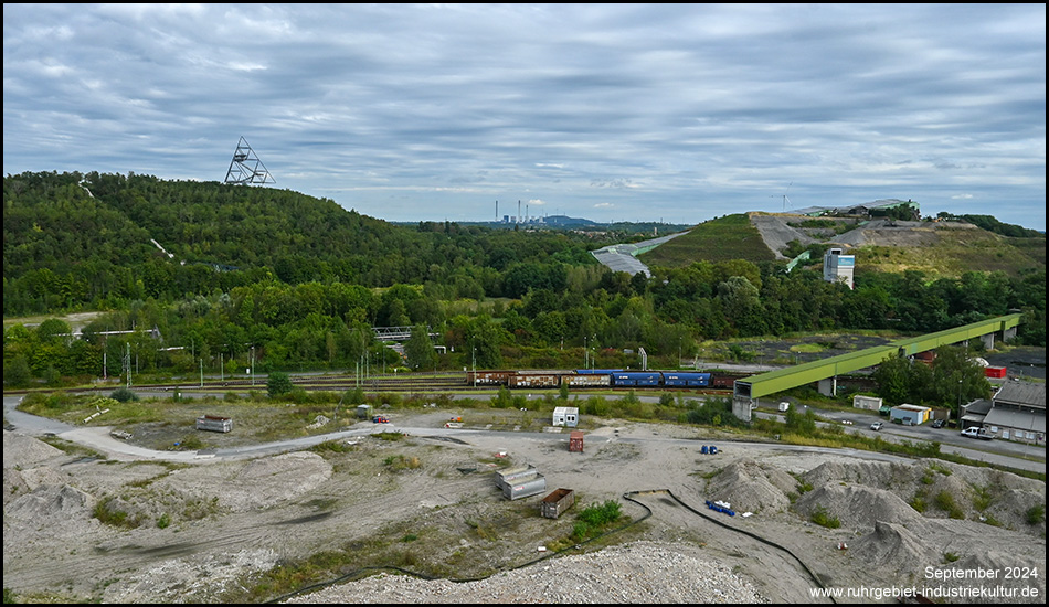 Zwei Halden nebeneinander. Zu sehen sind der Tetraeder auf der Halde Beckstraße und das Alpincenter als langgestrecktes Gebäude von der Halde Prosperstraße. Davor eine Brachfläche.