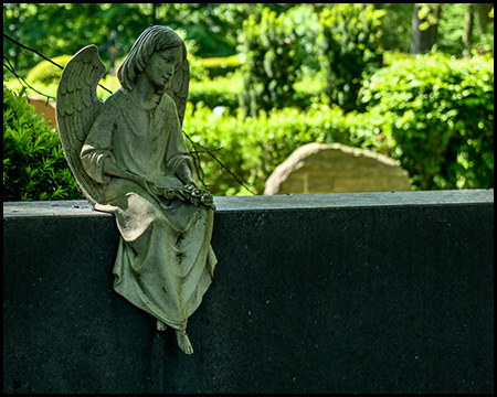 Ein kleiner Engel sitzt auf einer Grabstein-Oberkante