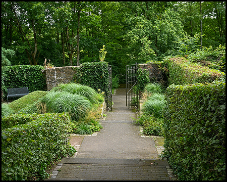 Eingang zu einem Park mit Hecken und grünen Büschen
