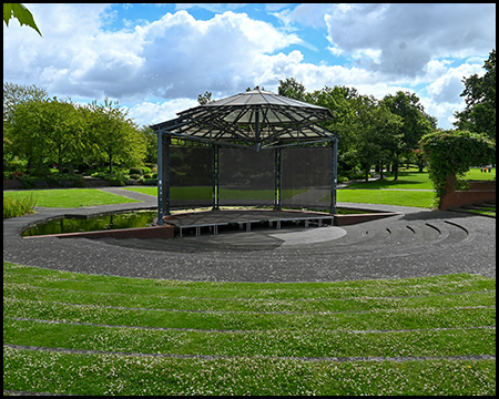 Eine Bühne, die von ringförmigen Tribünen in einer Wiesenfläche umrundet wird