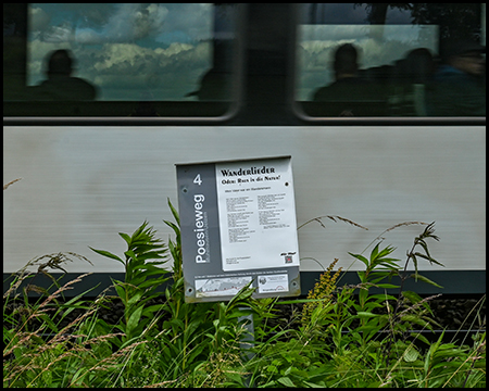 Station des Poesiewegs mit vorbeifahrendem Zug im Hintergrund