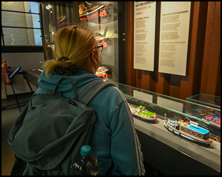 Eine Frau betrachtet Modellschiffe in einer Vitrine