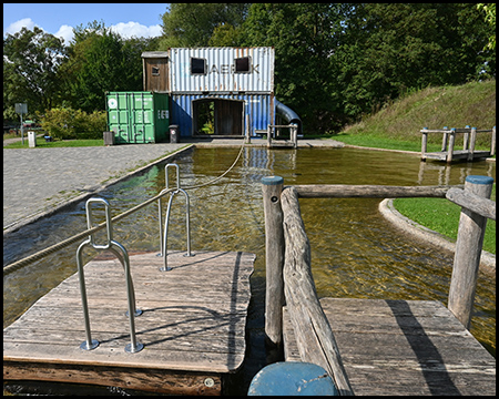 Floß auf einer kleinen Wasserfläche mit Frachtcontainern