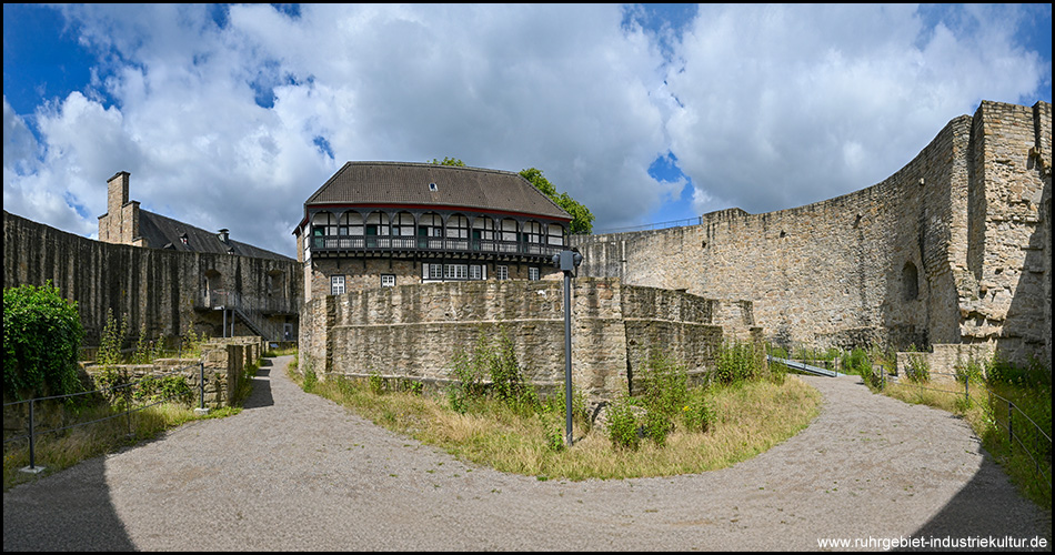 Breites Foto vom Innenhof von Schloss Broich mit Ruinen von Mauern und einem Gebäude mit Fachwerk-Obergeschoss