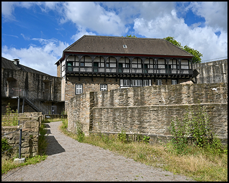 Reste von Burgmauern und ein Gebäude mit Fachwerk