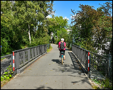 Eine Radfahrerin fährt auf einem Radweg über eine Brücke