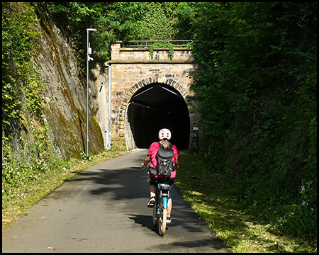 Radfahrerin auf einem Radweg vor einem Tunnelportal