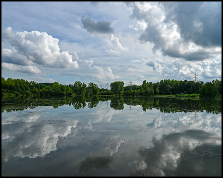 Eine ruhige Wasserfläche, in der sich dramatische Wolken spiegeln