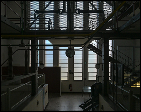 Großes Fenster in einer Halle mit Quer verlaufenden Leitungen und einer Uhr