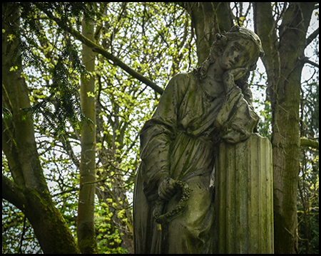 Eine Figur auf einem Friedhof stützt sich auf eine Säule auf