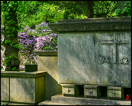 Ein großer Grabstein einer monumentalen Grabstätte mit Rhododendren im Hintergrund