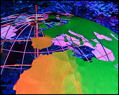 Eine Skulptur einer Weltkugel, die farbig beleuchtet in einem Park steht