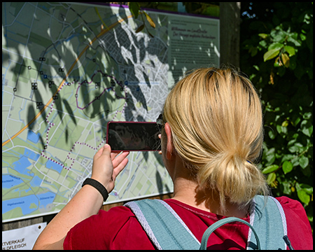 Eine Frau fotografiert mit einem Smartphone eine Wanderkarte zum Wildpark Dülmen