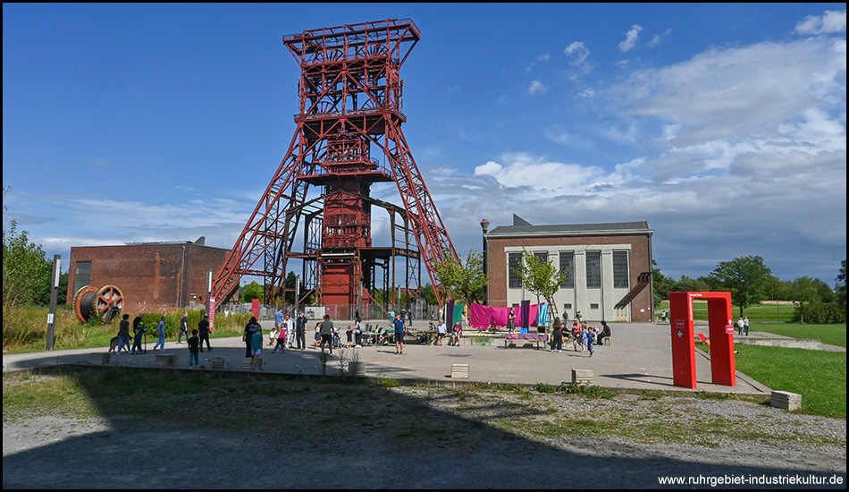 Ein großes rotes Fördergerüst eines Bergwerks mit benachbarten Maschinenhallen