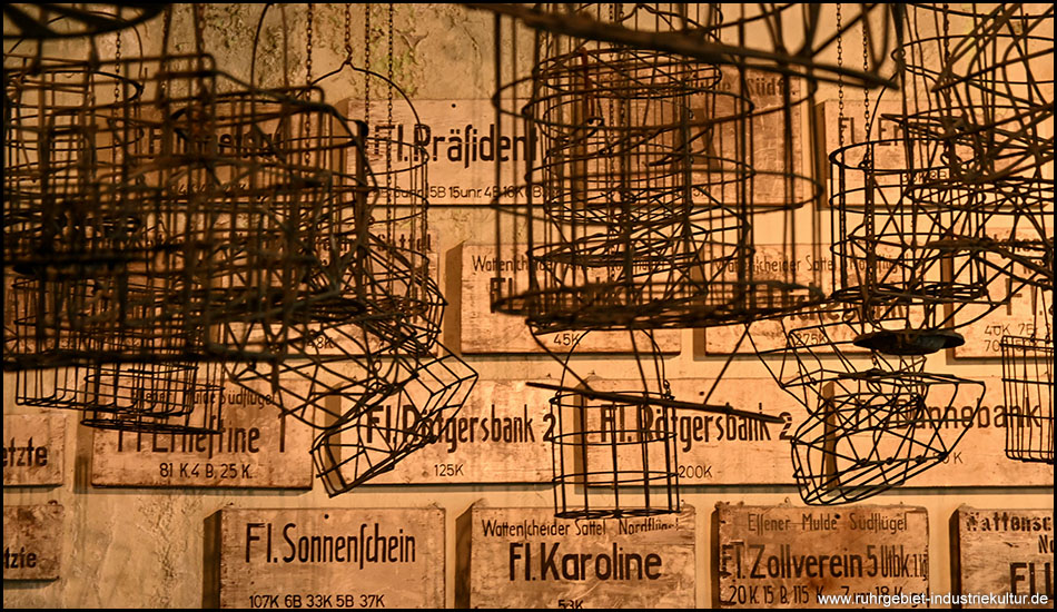 Drahtkörbe, bekannt von Waschkauen von Bergämnnern, unter der Decke. Dahinter Schilder von Flöz-Namen